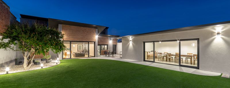 Patio interior de vivienda con txoco y vista del salon iluminado.