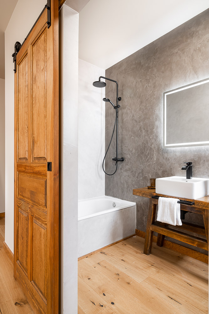 Baño con puerta corredera de madera estilo granero y microcemento gris