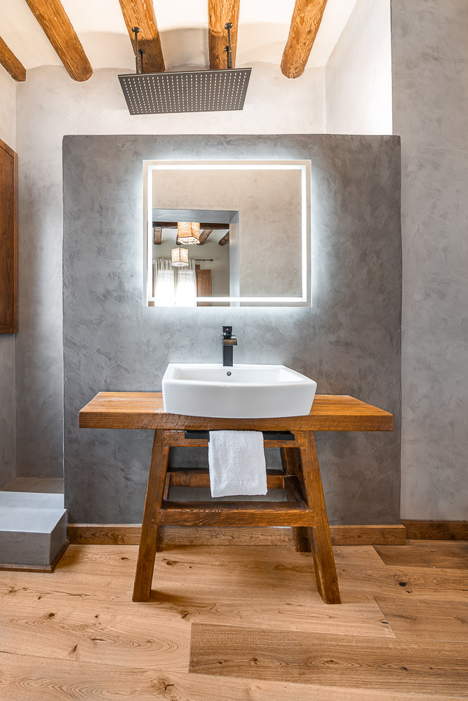 Baño con lavabo de diseño, vigas vistas y ducha efecto lluvia - reforma en Navarra