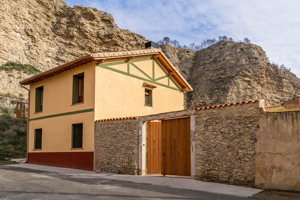 Fachada de Casa Dezerto, vivienda rural reformada junto a formación rocosa en Navarra