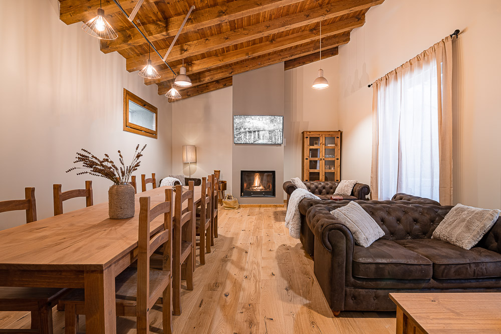 Salón con chimenea, sofá chester y techo de madera - proyecto de arquitectura en Ribera de Navarra