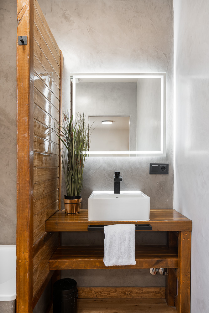 Lavabo de diseño sobre mueble de madera con espejo retroiluminado