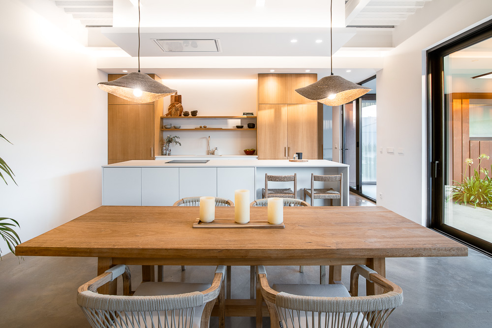 Mesa de comedor de madera con vista a cocina abierta - proyecto residencial Arquitectura de la Ribera
