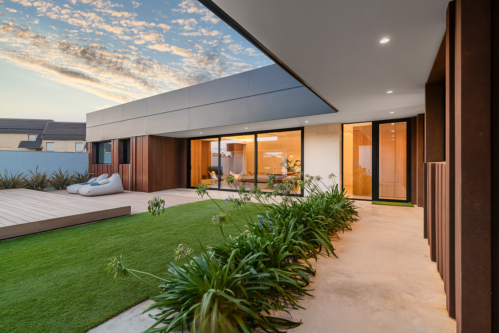 Terraza y jardín con césped artificial y fachada de acero corten - Casa Silis