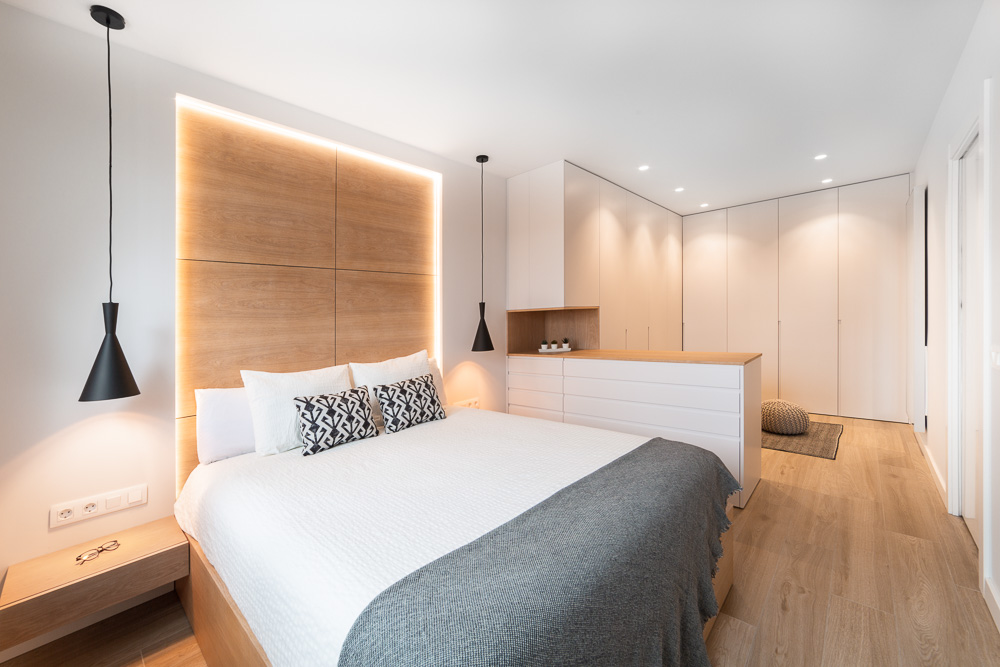 Dormitorio principal con cabecero de madera iluminado y vestidor integrado - Casa Tilio, Navarra