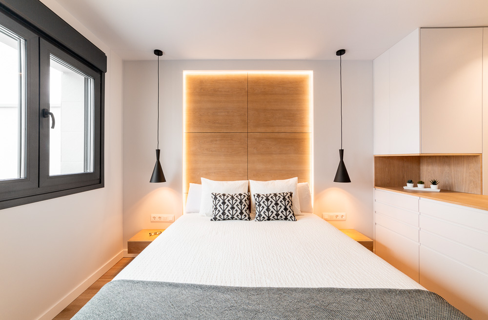 Dormitorio con cama doble, cabecero de madera retroiluminado y ventana - Casa Tilio
