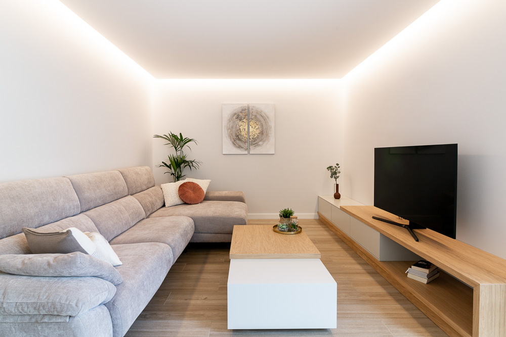 Salón con sofá, mueble de televisión de madera e iluminación perimetral - Casa Tilio, Navarra