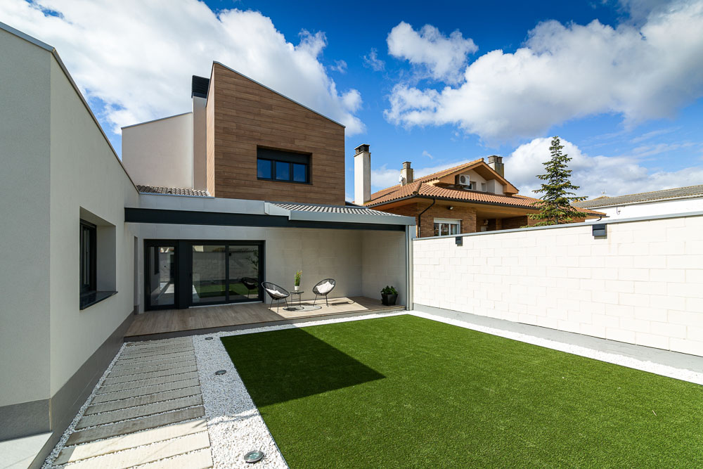 Patio y jardín trasero con porche cubierto y césped - Casa Tilio, Arquitectura de la Ribera