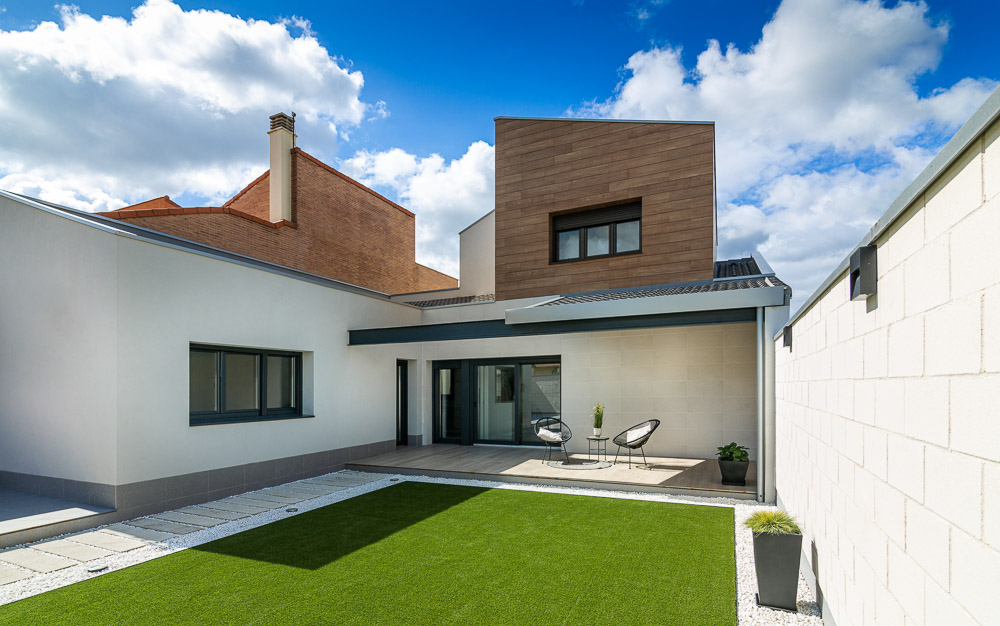 Jardín trasero con zona de estar exterior y fachada de vivienda - Casa Tilio, Navarra