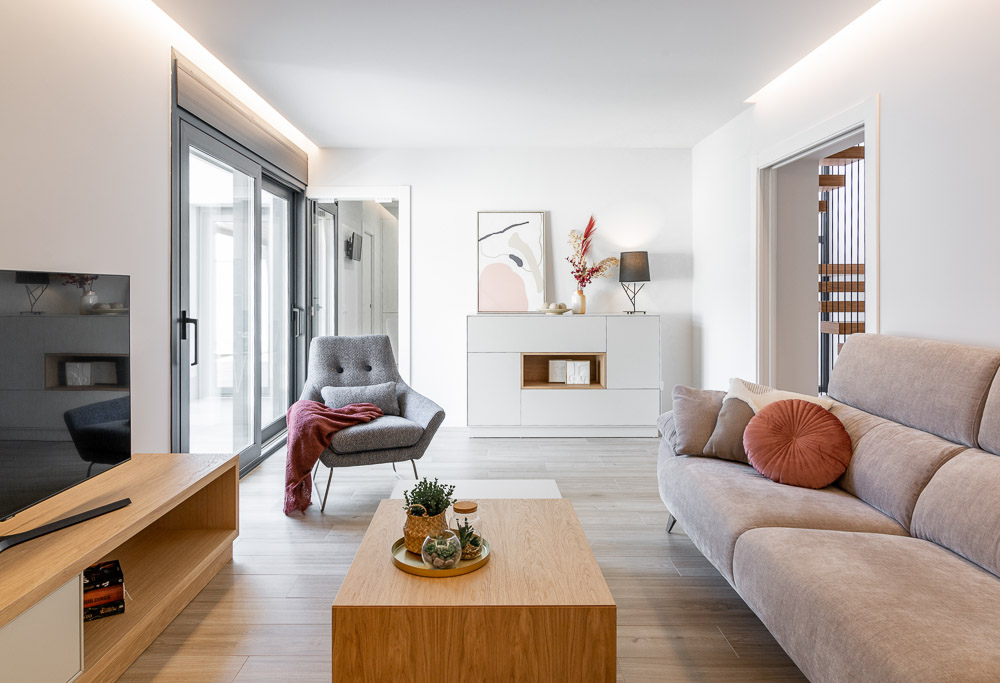 Salón con sillón, sofá y mueble bajo de televisión en tonos neutros - Casa Tilio