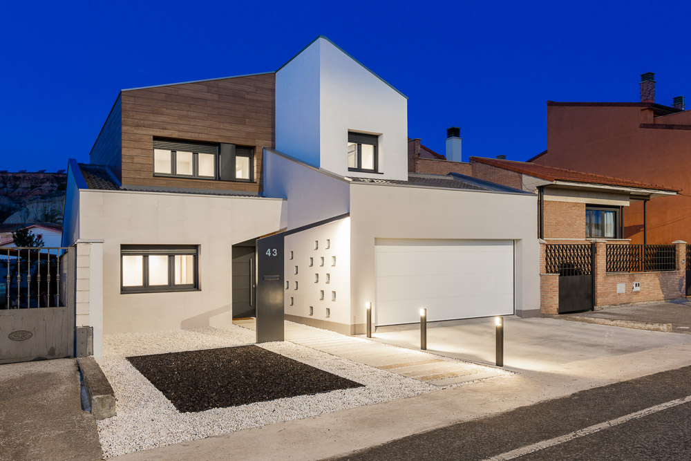 Vista frontal nocturna de la fachada con iluminación de acceso - Casa Tilio, Navarra