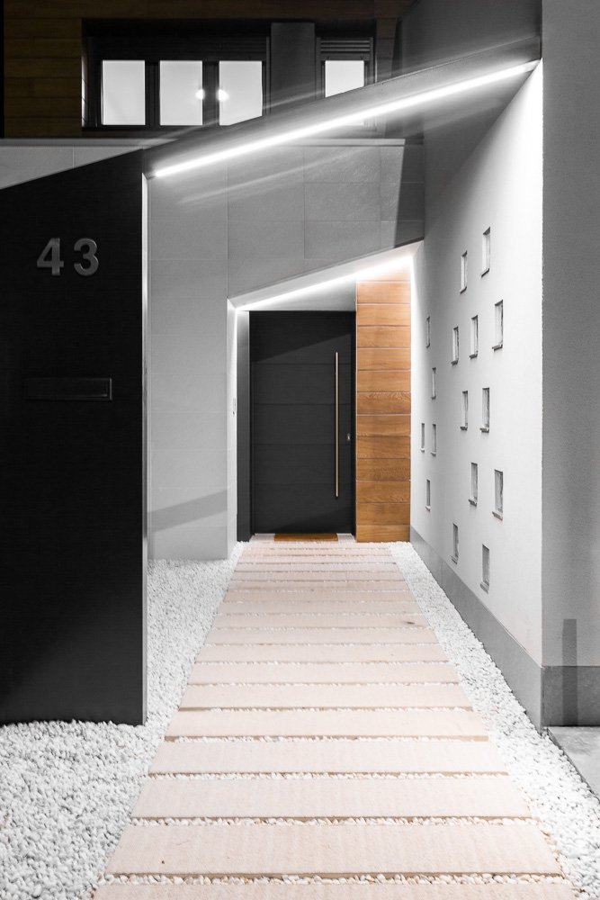 Acceso principal con iluminación led y puerta de entrada en madera - Casa Tilio, Navarra