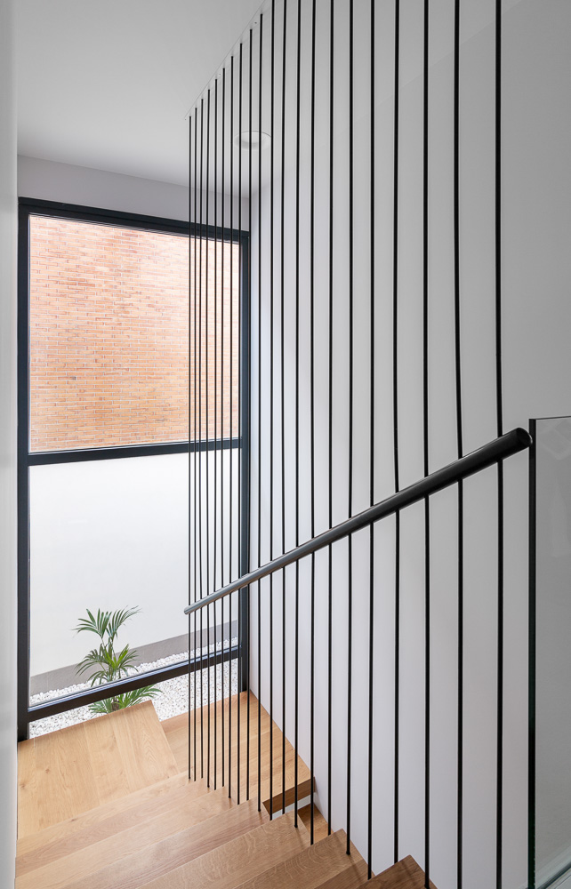 Detalle de escalera volada con barandilla de varillas metálicas - Casa Tilio