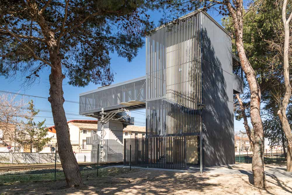Pasarela peatonal metálica sobre las vías del tren con torre de acceso - Arquitectura de la Ribera, Navarra