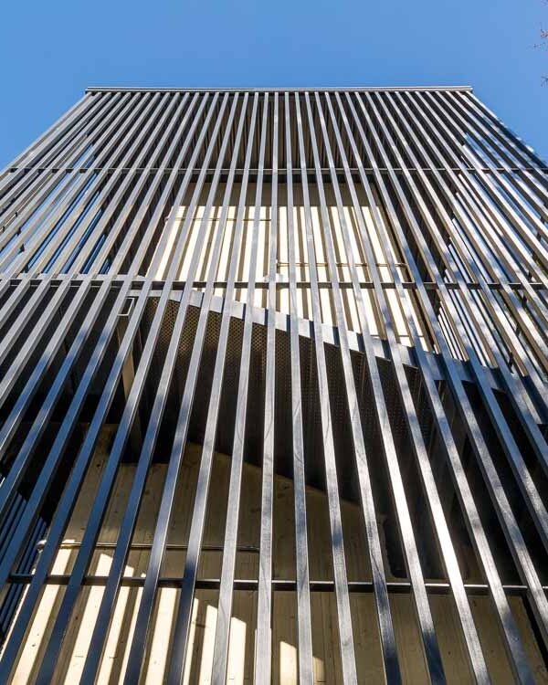 Detalle de fachada de lamas verticales metálicas en torre de acceso a pasarela