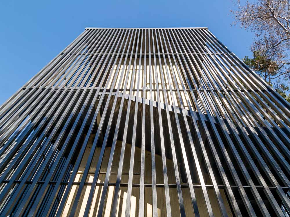 Detalle de fachada de lamas verticales metálicas en torre de acceso a pasarela