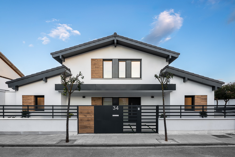 Fachada principal de vivienda unifamiliar blanca con cubierta a dos aguas y detalles en madera, proyecto en Corella