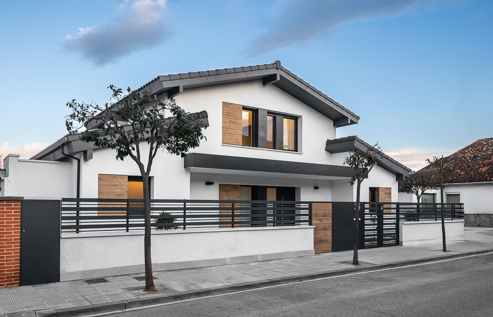 Vivienda unifamiliar con cerramiento de lamas oscuras y jardín delantero, obra de Arquitectura de la Ribera en Navarra