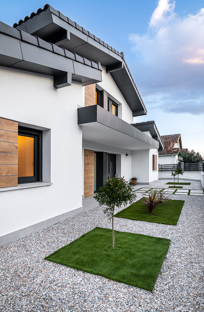 Fachada lateral blanca con jardín de grava y césped, arquitectura contemporánea en Corella