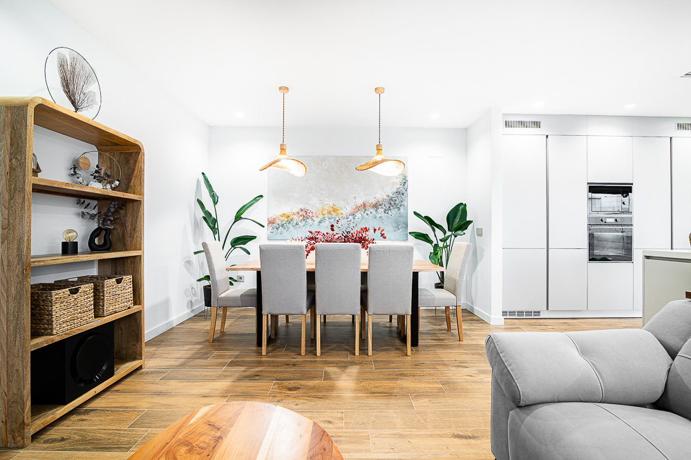 Comedor abierto con lámparas doradas y estantería de madera, interiorismo de Arquitectura de la Ribera en Navarra