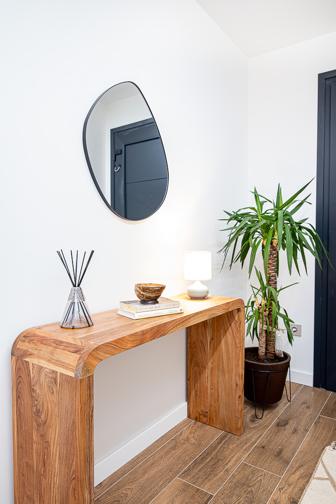 Recibidor con consola de madera maciza y espejo orgánico, interiorismo de Arquitectura de la Ribera