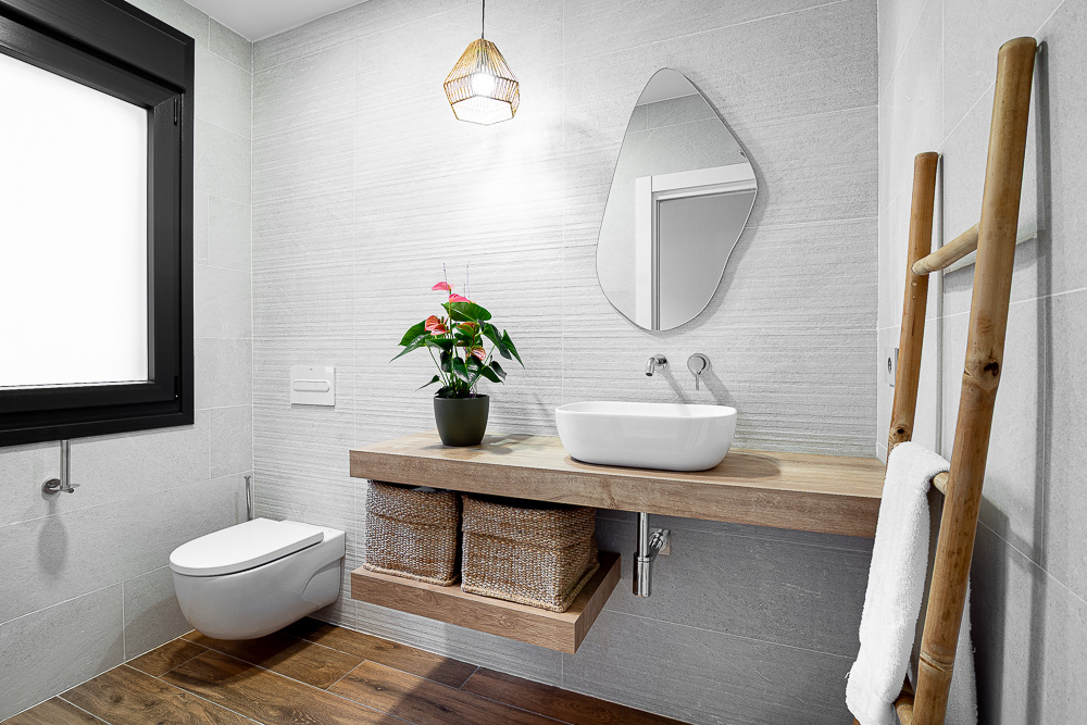 Baño en gris con espejo orgánico y lavabo sobre balda de madera, diseño de arquitecto en Cintruénigo, Navarra