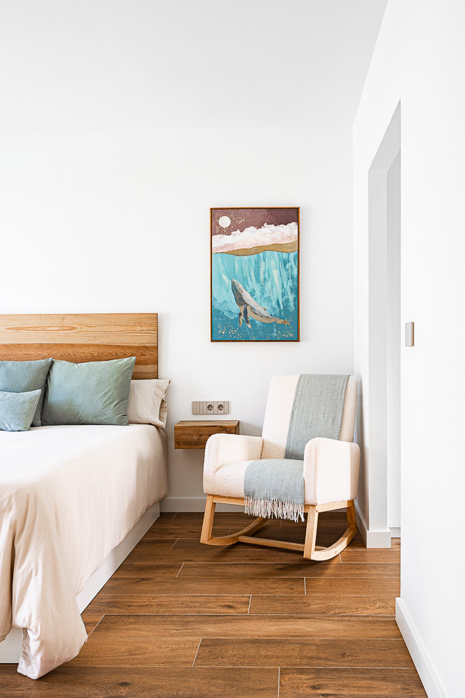 Rincón de dormitorio con mecedora y cabecero de madera, interiorismo residencial en Cintruénigo