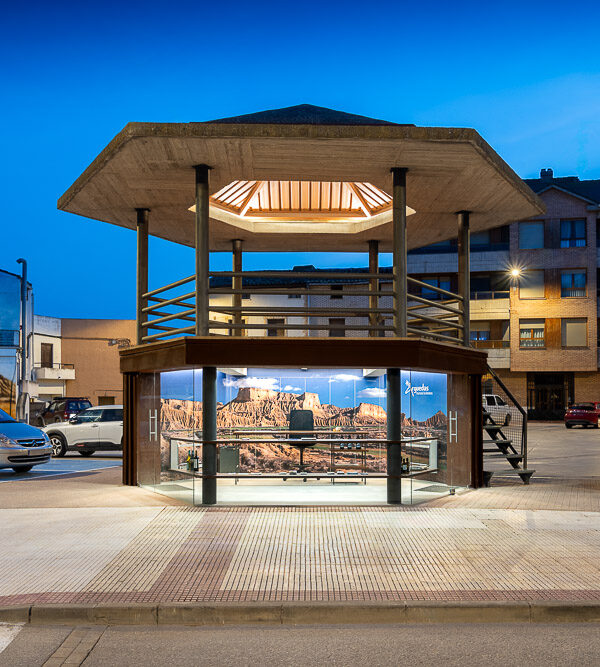 Vista nocturna del centro de información con planta baja acristalada y mural de las Bardenas, obra de Arquitectura de la Ribera en Arguedas