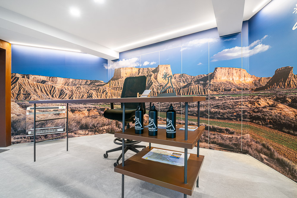 Puesto de atención con expositor de productos locales e iluminación lineal, diseño interior de centro de información en Navarra