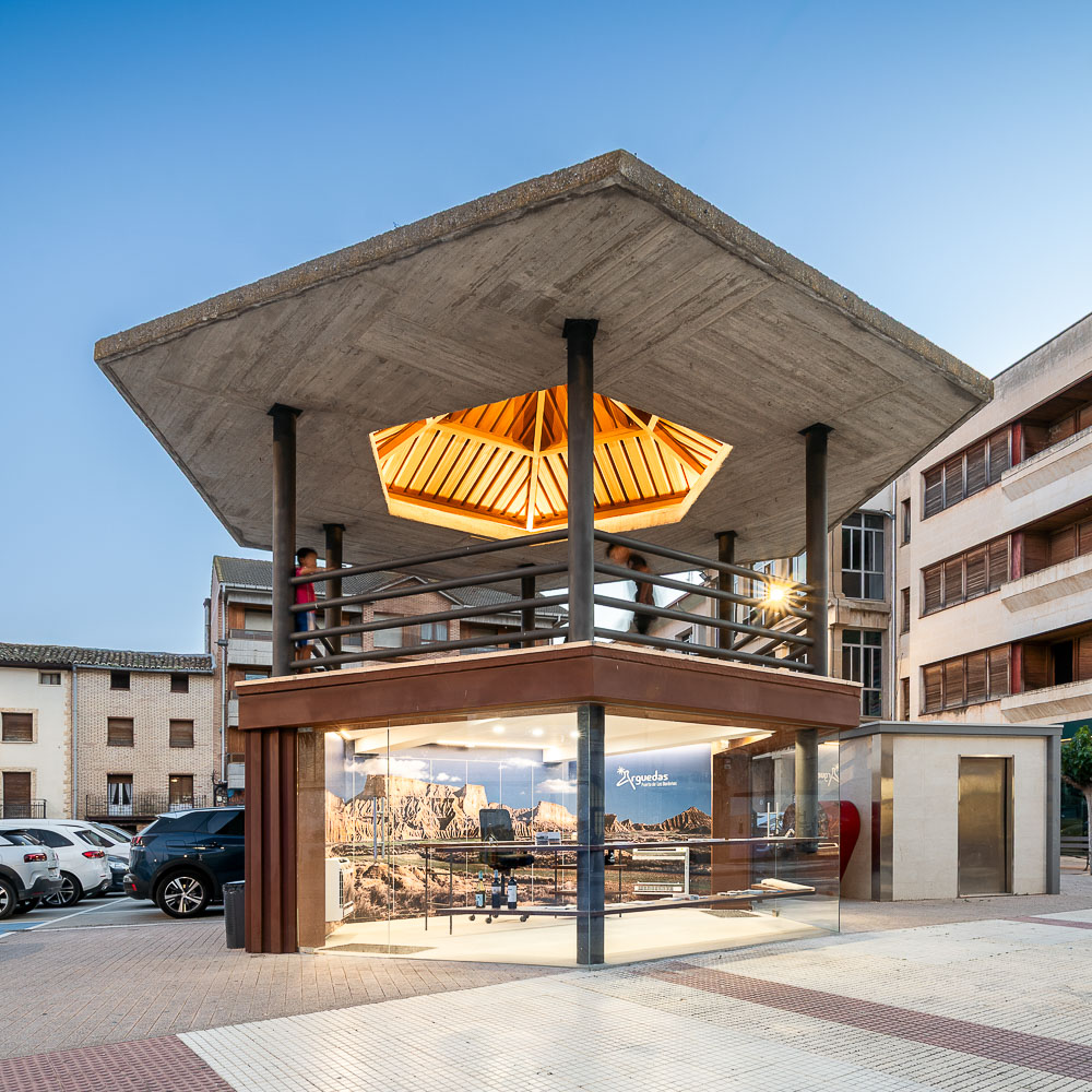 Pabellón con cubierta de hormigón volada y techo de lamas de madera iluminado, arquitectura pública en Arguedas, Navarra